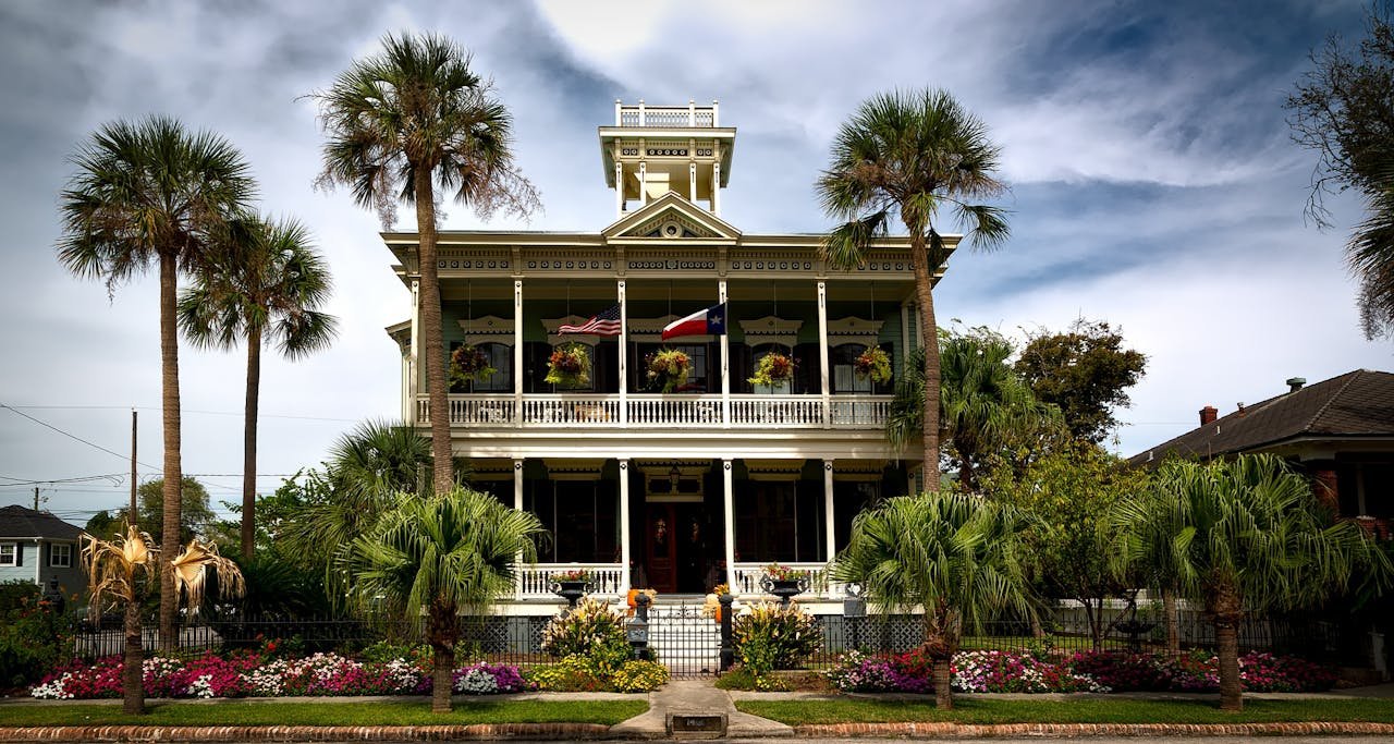 White Painted Structure With Green Palm Trees in the Front